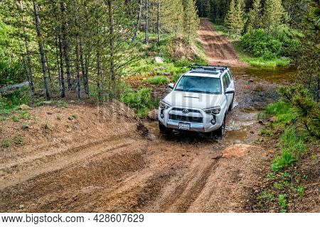 RED FEATHER LAKES, CO, USA - JUNE 3, 2016: Toyota 4Runner SUV (2016 Trail edition) crossing a mountain stream (Sand Creek Road) in Colorado's Rocky Mountains