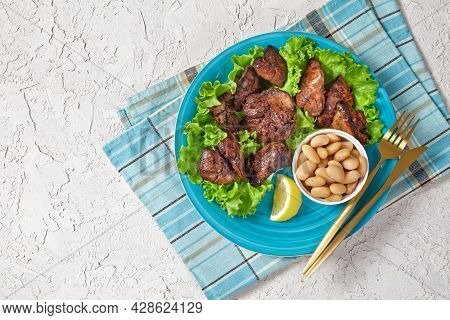 Chicken Liver Fry, Kaleji Fry, Served On Lettuce Leaves With Butter Beans And Lemon Wedges On A Blue