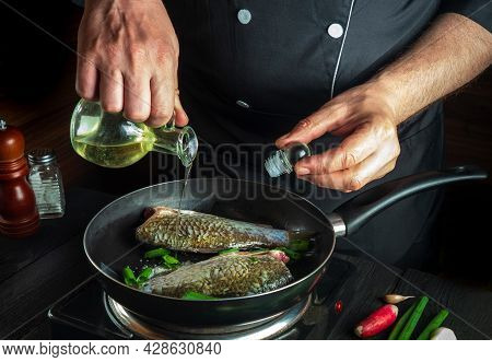 Chef Prepares Fresh Fish In Pan With Oil. Preparation For Cooking Fish Food. Working Environment In 