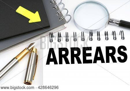 Business And Finance Concept. On The Table Are A Pen And A Notebook With The Inscriptions - Arrears