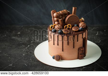 Chocolate Cake Decorated With Blueberries, Cookies And Bubble Chocolates On A Black Background. Brow