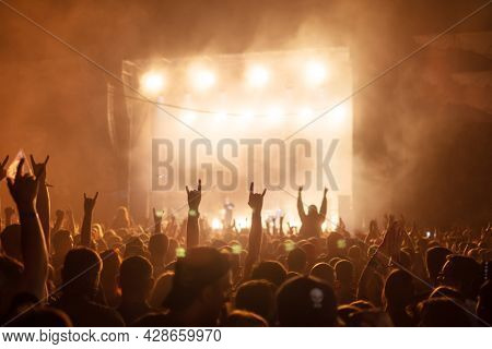 Silhouettes of concert crowd in front of bright stage lights. Rock and metal music concept