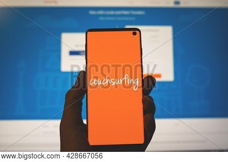 Couchsurfing Logo On Smartphone In Hand With Blurred Website Background. Hospitality Exchange Servic