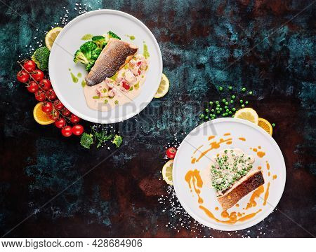 Two Dish. Roasted Salmon Steak And Sibas Steak With Vegetables On White Plates On Blue Textured Back