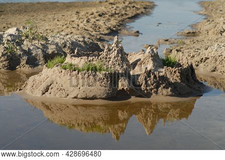 Background With A Sandcastle And Its Reflection In The Water. Summer Vacation Concept. Children Ente