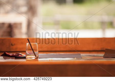 Selective Blur On An Empty Glass With A Black Single Use Plastic Straw On The Table Of A Bar Restaur