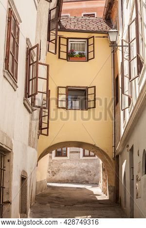 Empty Picturesque Medieval Narow Street With A Bridge House Over An Arcade In The Historical Center 