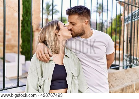 Young caucasian couple of boyfriend and girlfriend having fun outdoors on a un sunny day kissing in love