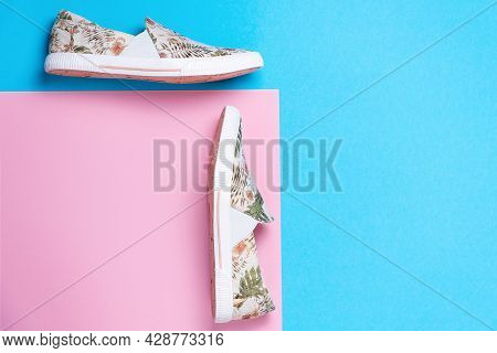 Pair Of A New Female's Slip-ons Made Of Floral Pattern Canvas On A Pink-blue Background. Flat Lay. C
