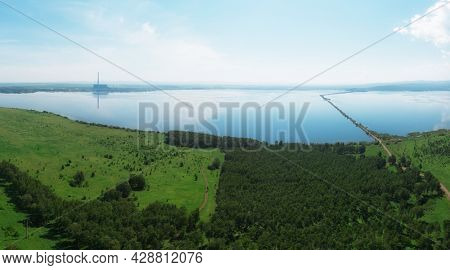 Beryozovskoye reservoir - cooling reservoir of Beryozovskaya GRES. Aerial drone view of lake landscape with road in sunny summer. Berezovskaya GRES is a thermal power plant in the town of Sharypovo