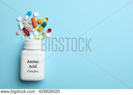 Plastic Bottle With Amino Acid Complex And Pills On Light Blue Background, Flat Lay. Space For Text