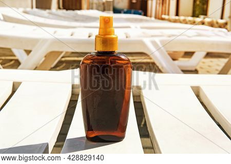 Bottle With Suntan Cream On Deckchair. Sunburn And Cancer Prevention Concept. Copy Space. Place For 