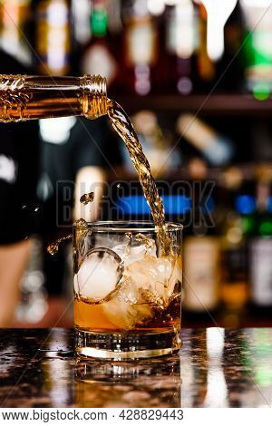 Whiskey Is Poured Into Glass. Glass Of Whiskey On Bar Counter In Restaurant. High Quality Photo