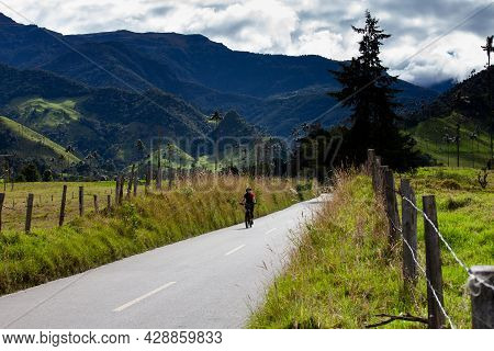 Salento, Colombia - July 2021. Woman Riding Her Bike On The Beautiful Landscapes Of The Cocora Valle