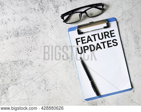 Business And Finance Concept. Selective Focus Paper Clipboard Written Feature Updates With Pen And E