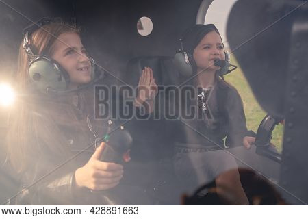 Two Preteen Girls In Headsets Sitting In Helicopter Giving High Five