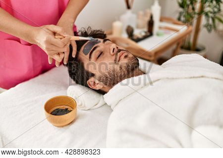 Man reciving facial treatment at beauty center.