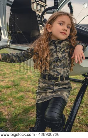 Preteen Girl In Camouflage Style Dress Standing Leaning On Helicopter