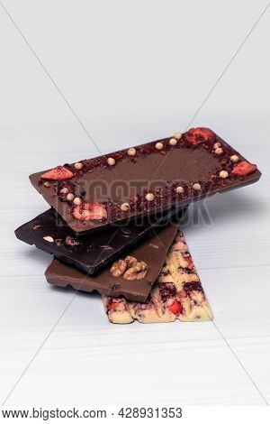 Different Kinds Fof Chocolate Bars Stacking On White Wooden Background. Dark One, Milk And White, Wi