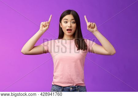 Excited Cute Surprised Asian Girl In Pink T-shirt Telling About Awesome News Pointing Raised Fingers