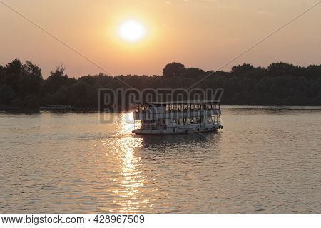 Boat With Tourists In The Rays Of Sunlight At Sunset.