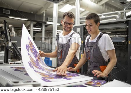 Graphic Engineers Or Workers Checking Imprint Quality In Modern Print Shop.
