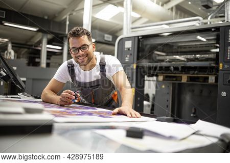 Print House Worker Controlling Printing Process Quality And Checking Colors With Magnifying Glass.