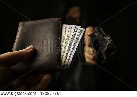 Armed Robbery. Assault On Unarmed Man. Mans Hand Holds Out Wallet Of Money To Robber With Gun. Hundr