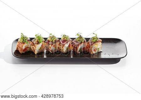 Japanese sushi roll with japanese omelette - tamagoyaki. Sushi roll with avocado and cream cheese inside, topped with fried tuna. Delicious sushi roll with fish topped with sauce and fresh greens