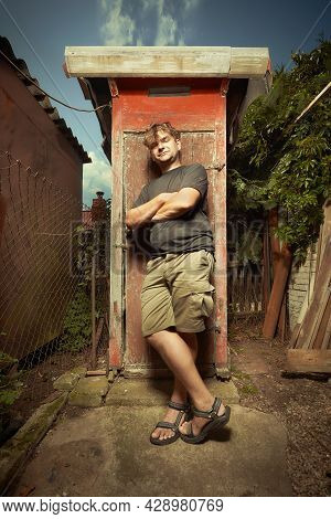 Man Leaving Wooden Toilet Latrine On Summer Cottage