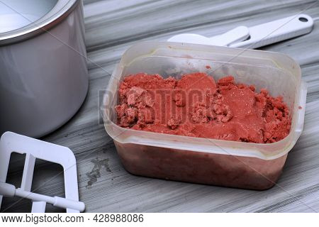 Homemade Cherry Ice Cream In A Plastic Container On The Table Next To An Ice Cream Spoon And An Ice 