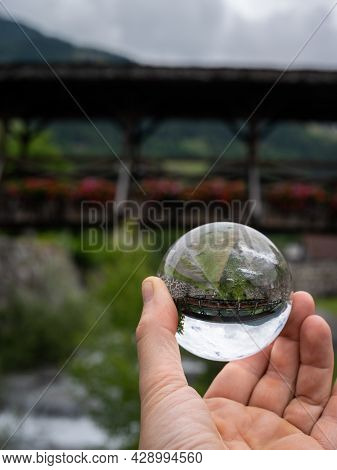 Old Wooden Bridge With Flowers In Matrei In Osttirol Seen Through Glass Sphere, Cloudy Day In Summer