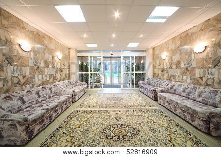 Spacious light hall with sofas at the walls of a holiday home