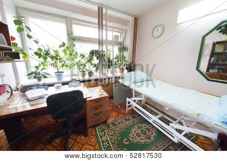 Interior of a light doctors consulting room with a bed and a workplace