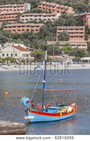 Kalami bay, Corfu, with new holiday villas on the cliff and a traditional fishing boat moored in the foreground. The cove in north-east Corfu was made famous by writer Lawrence Durrell.