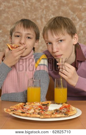 Two boys eatning pizza