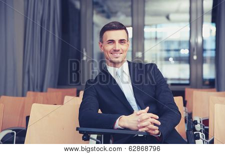 Smiling businessman sitting at conference hall