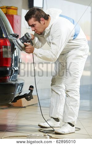 auto mechanic worker polishing car at automobile repair and renew service station shop by power buffer machine