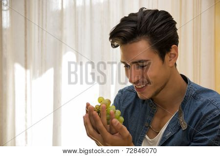 Young Man Holding A Ripe Bunch Of Grapes