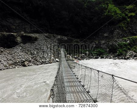 Traditional Suspension Bridge Crossing A Wild River