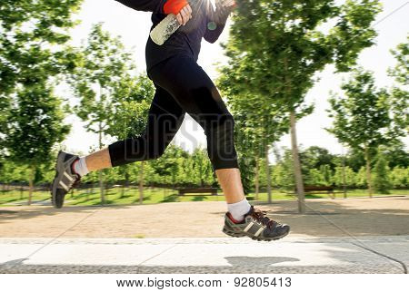 Close Up Legs Of Young Man Running In City Park With Trees On Summer Training Session Practicing Spo