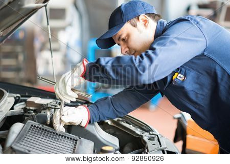 Portrait of an auto mechanic at work on a car in his garage