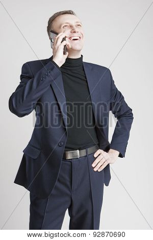 Epressive Handsome Caucasian Man In Elegant Siut Speaking By Cell Phone And Smiling. Against White