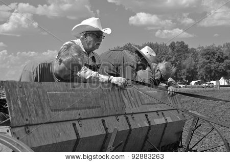 Farmers spreading seed oats in drill box