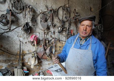 Resen, Macedonia - May 28, 2015 : Old Blacksmith With Hammer In A Hand Poses At His Workshop