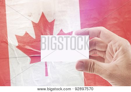 Man Holding Blank Business Card Against Canada National Flag