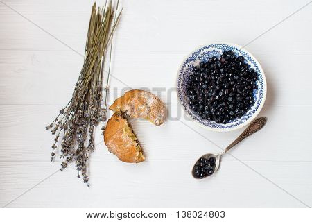 A flat lay of a blueberry muffins blueberry bowl and flowers of lavender on a white background