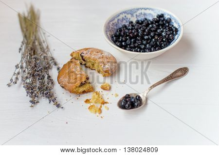 A flat lay of a blueberry muffins blueberry bowl and flowers of lavender on a white background