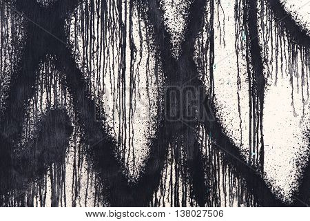 White concrete wall with black paint drips, drops and stains. Abstract background, rough grunge graffiti texture, dirty and messy old urban wall surface.