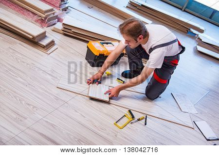 Man laying laminate flooring in construction concept